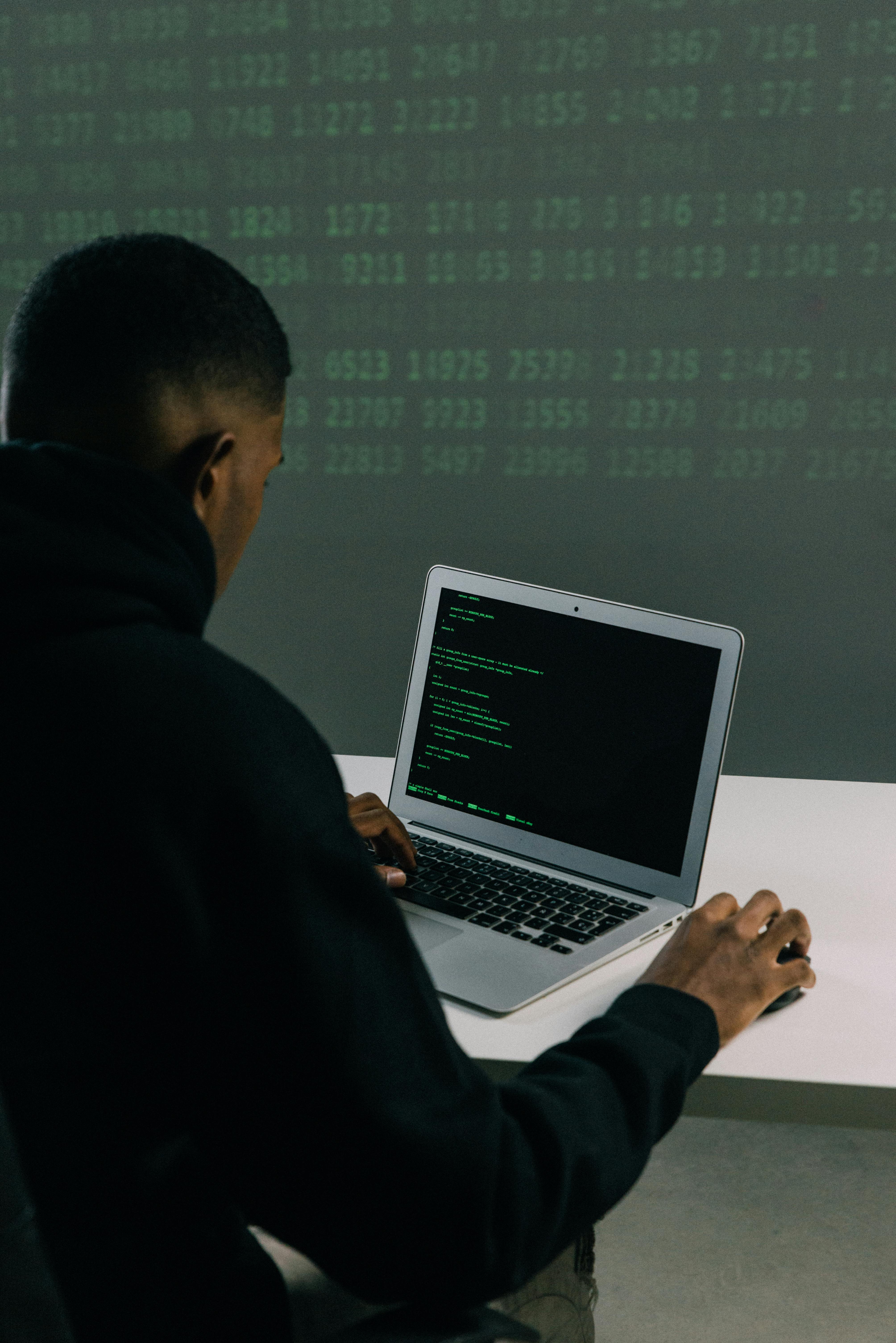 Developer coding on laptop with data in background