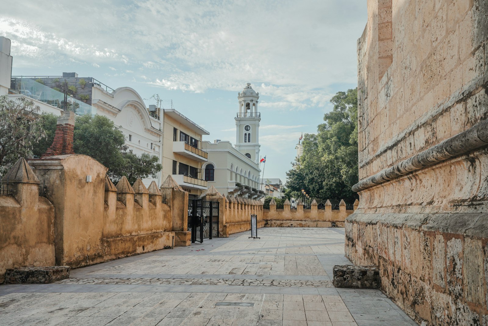 Quiet street in Santo Domingo's Zona Colonial, with a clock tower, colonial stone walls and a Dominican flag